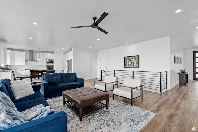 living room with recessed lighting, a ceiling fan, light wood finished floors, and baseboards