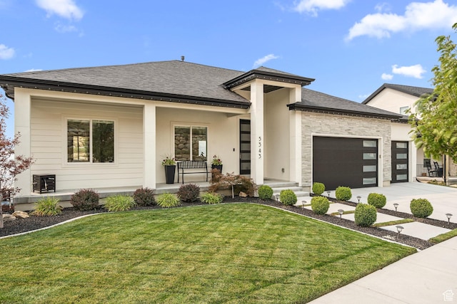 prairie-style house with a porch, an attached garage, concrete driveway, a front yard, and roof with shingles