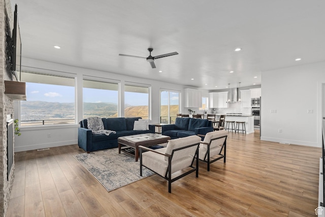 living area featuring a ceiling fan, light wood finished floors, baseboards, and recessed lighting