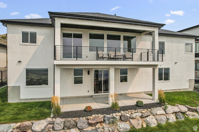 back of property with a balcony, a patio, and stucco siding