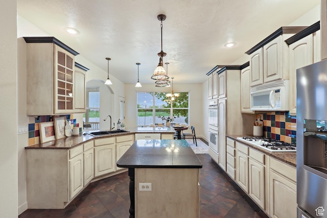 kitchen featuring white appliances, a sink, a peninsula, backsplash, and a kitchen island
