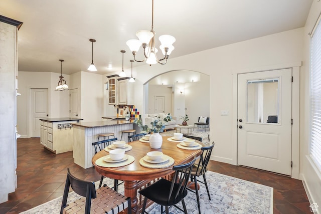 dining space with arched walkways, a chandelier, and plenty of natural light