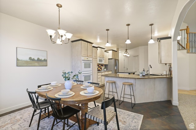 dining area with arched walkways, baseboards, and a chandelier