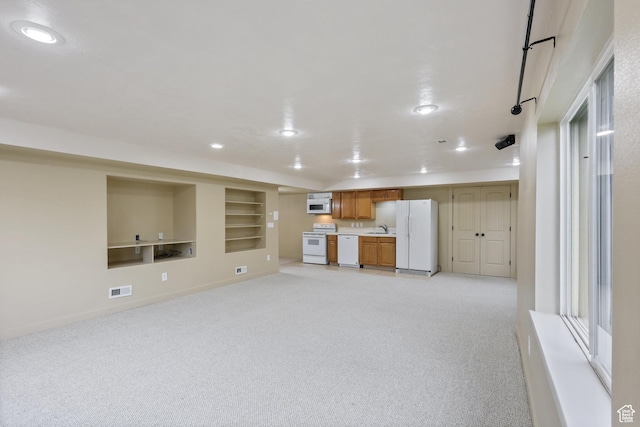 unfurnished living room featuring a sink, light colored carpet, recessed lighting, baseboards, and built in shelves