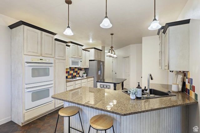kitchen featuring white appliances, a sink, a peninsula, a breakfast bar area, and decorative backsplash