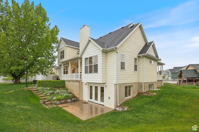 back of house with a patio area, a lawn, a chimney, and roof with shingles