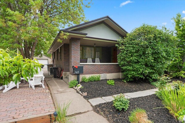162 E Cleveland, Salt Lake City, UT 84115 - view of front of property with brick siding, an outdoor structure, stucco siding, covered porch, and a detached garage