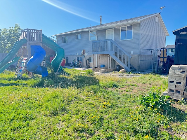 rear view of property featuring a playground, fence, and a gate