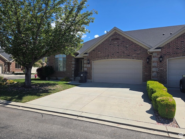 single story home featuring a garage, concrete driveway, brick siding, and a shingled roof