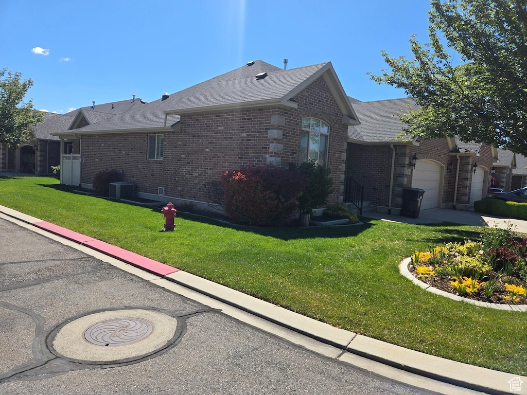 view of side of home with brick siding, an attached garage, a yard, and roof with shingles