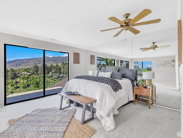 bedroom featuring access to outside, light carpet, a mountain view, a ceiling fan, and baseboards