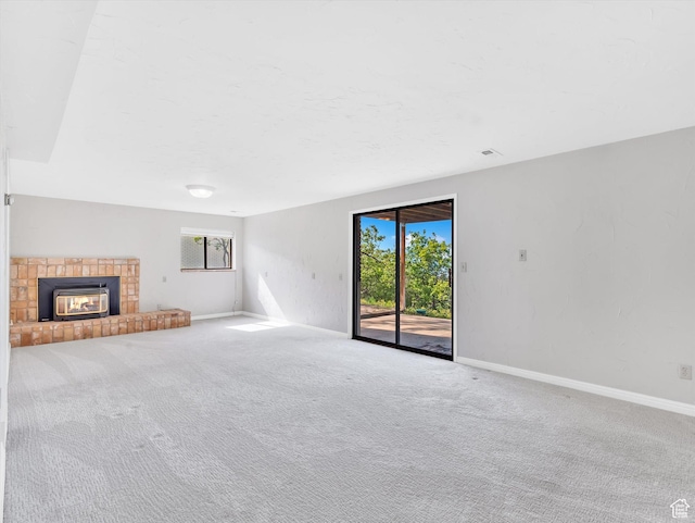 unfurnished living room with healthy amount of natural light, carpet floors, a brick fireplace, and baseboards
