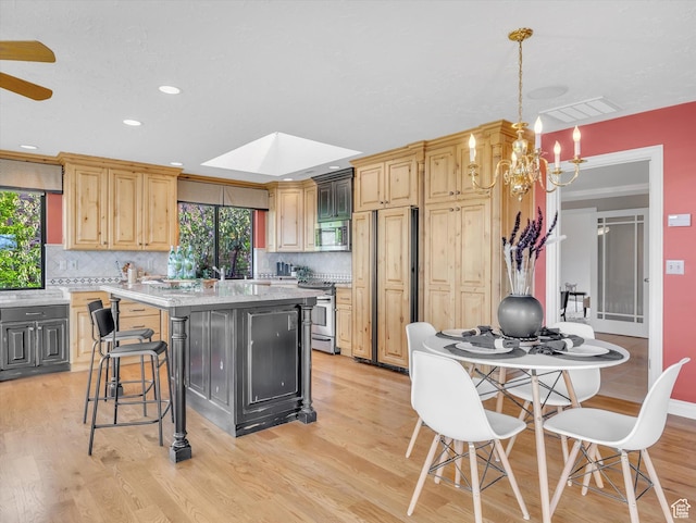 kitchen with appliances with stainless steel finishes, a chandelier, a kitchen island, backsplash, and recessed lighting