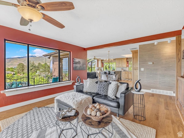 living room with baseboards, healthy amount of natural light, light wood-type flooring, and ceiling fan