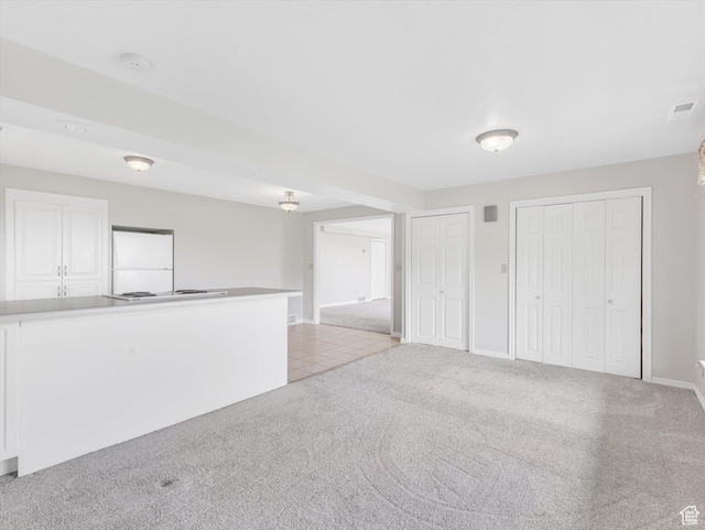 unfurnished living room featuring light colored carpet and baseboards