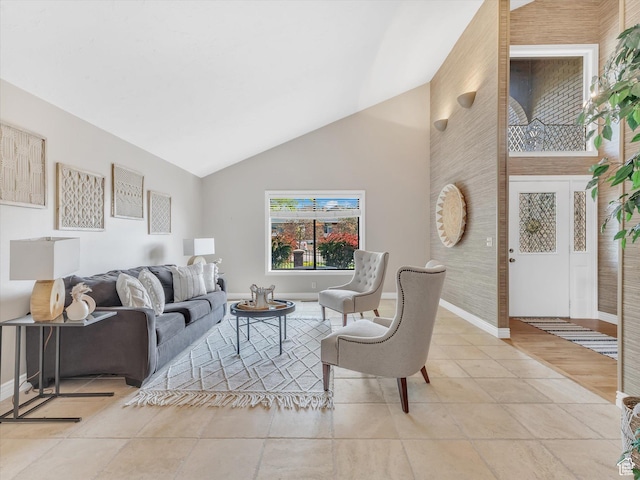 tiled living room featuring baseboards and high vaulted ceiling