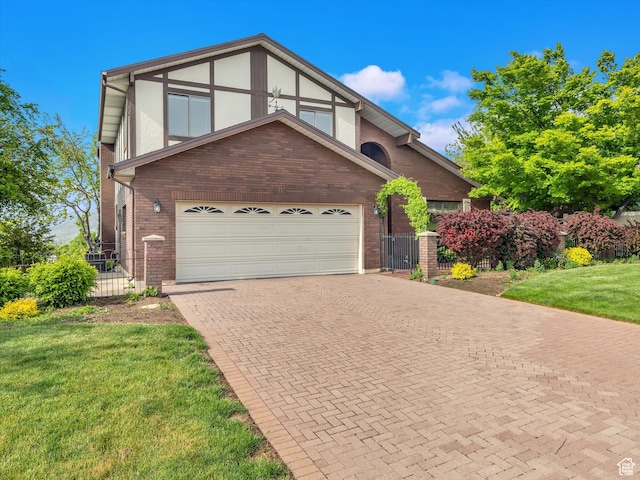tudor home with brick siding, decorative driveway, and a gate
