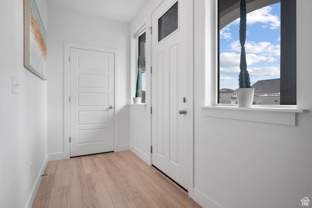 doorway featuring light wood-style flooring and baseboards