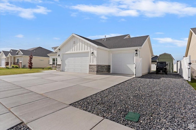 view of side of home with board and batten siding, a garage, driveway, stone siding, and fence