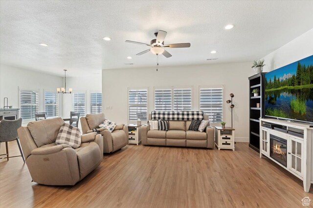 living area featuring light wood-type flooring, a textured ceiling, ceiling fan, a chandelier, and recessed lighting