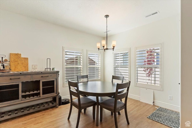 dining area with a chandelier, light wood finished floors, and baseboards