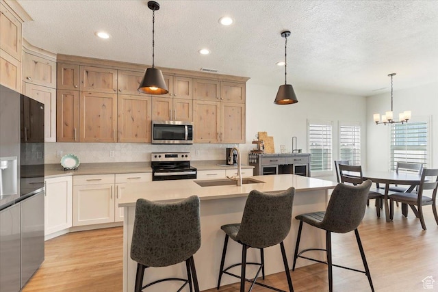 kitchen featuring appliances with stainless steel finishes, a sink, decorative backsplash, a chandelier, and a textured ceiling