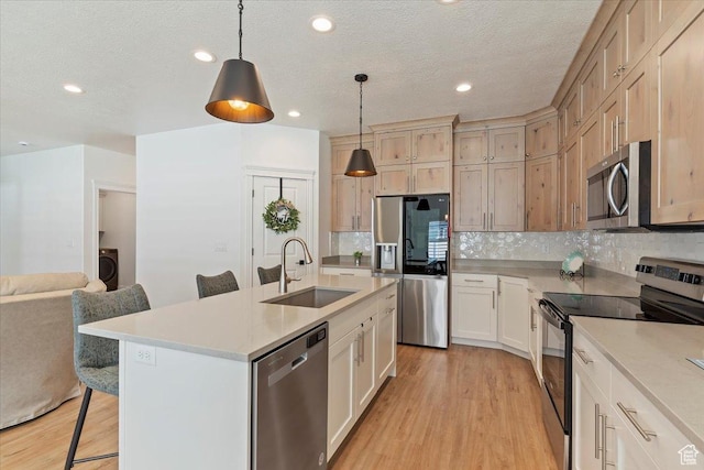 kitchen with appliances with stainless steel finishes, a sink, a breakfast bar area, light wood finished floors, and recessed lighting