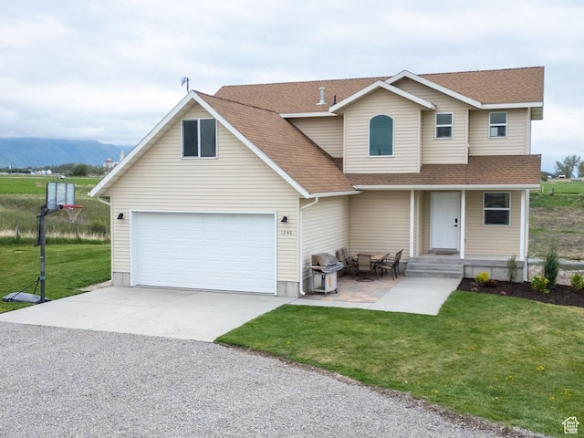 traditional-style house with a shingled roof, a front yard, a garage, driveway, and a mountain view