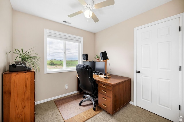 office space featuring baseboards, a ceiling fan, and light carpet