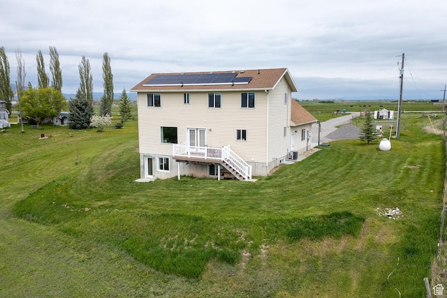 rear view of house featuring solar panels, stairs, a yard, and a deck