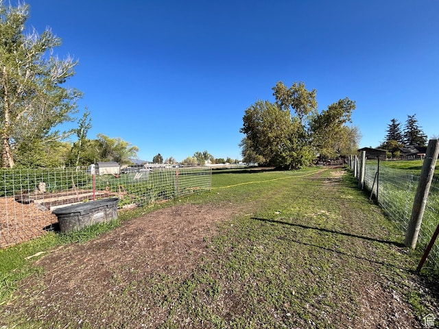view of yard with fence, a rural view, and a garden