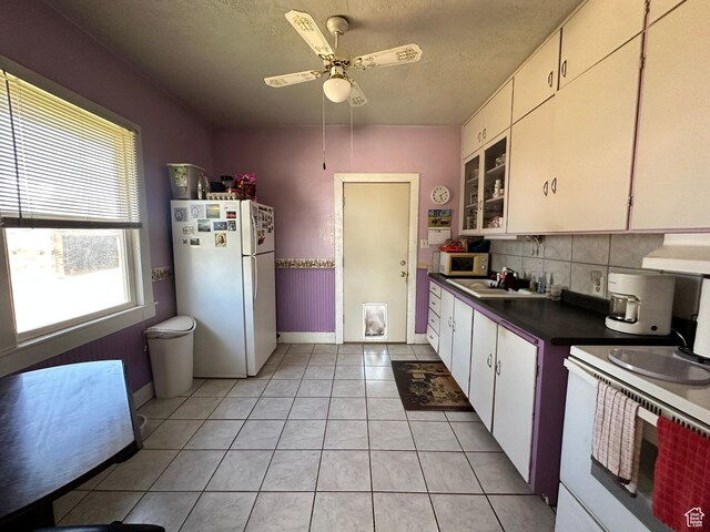 kitchen with white appliances, dark countertops, baseboards, tasteful backsplash, and light tile patterned floors