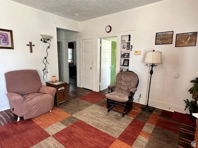 sitting room featuring a textured ceiling, baseboards, and wood finished floors