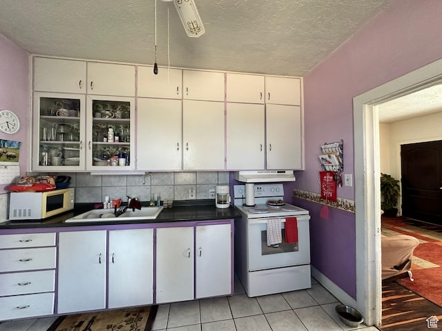 kitchen featuring white appliances, a textured ceiling, white cabinets, dark countertops, and light tile patterned floors