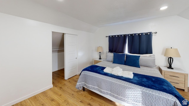 bedroom featuring vaulted ceiling, wood finished floors, a closet, baseboards, and recessed lighting