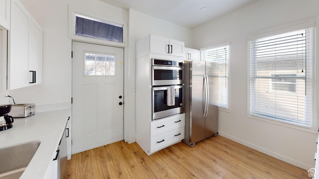 kitchen with appliances with stainless steel finishes, light wood-style floors, light countertops, and plenty of natural light
