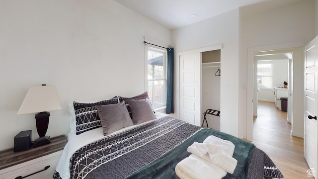bedroom featuring light wood-type flooring, washer / dryer, and a closet