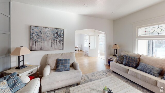 living room with arched walkways and wood finished floors