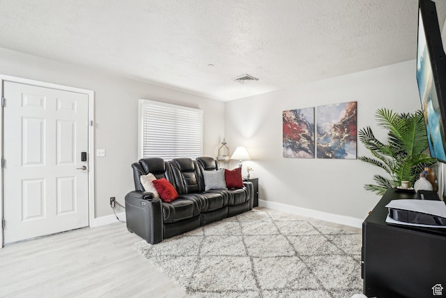 living area with a textured ceiling, baseboards, and wood finished floors
