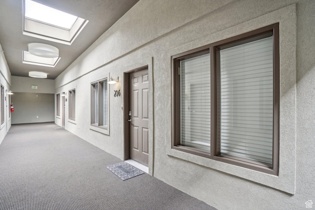 corridor with a textured wall, carpet floors, and a skylight