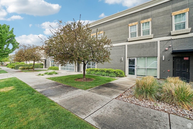 townhome / multi-family property with a front lawn and brick siding