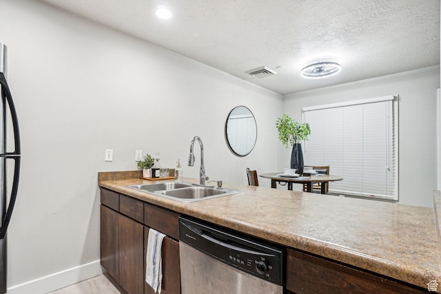 kitchen with stainless steel appliances, a sink, dark brown cabinetry, baseboards, and light countertops