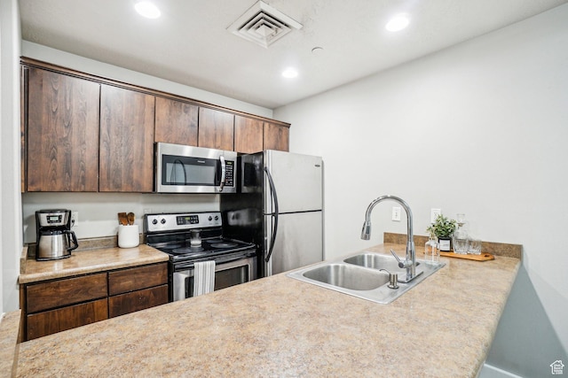kitchen with appliances with stainless steel finishes, a sink, recessed lighting, a peninsula, and light countertops
