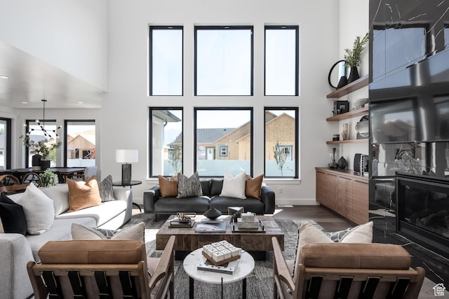 living room with wood finished floors, a towering ceiling, and baseboards
