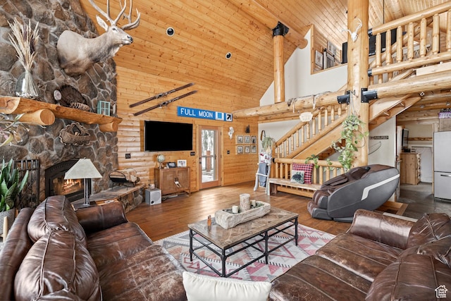 living area featuring high vaulted ceiling, hardwood / wood-style flooring, rustic walls, wooden ceiling, and a fireplace