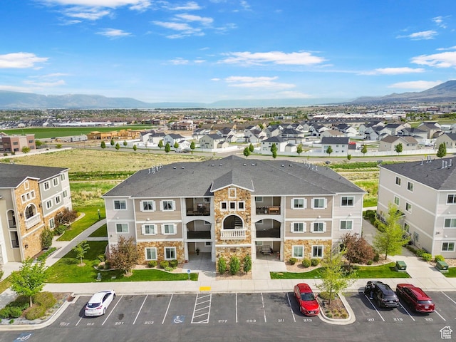 view of building exterior with uncovered parking, a mountain view, and a residential view