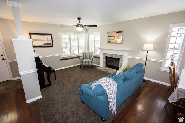 living area featuring a ceiling fan, a fireplace, decorative columns, and healthy amount of natural light