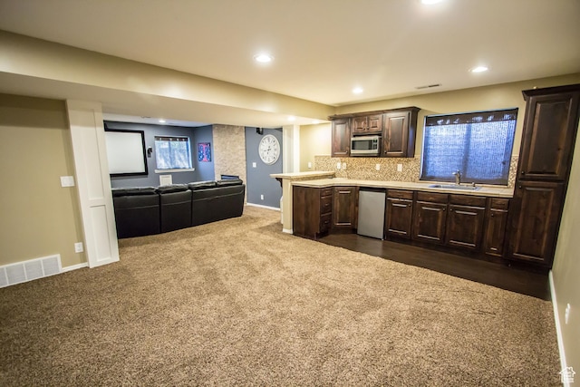 kitchen with stainless steel appliances, a sink, light countertops, dark brown cabinets, and dark carpet