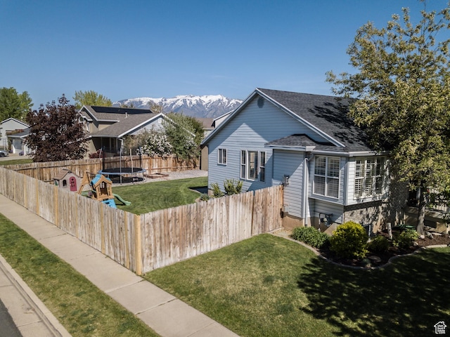view of front facade featuring a trampoline, a mountain view, and a shingled roof