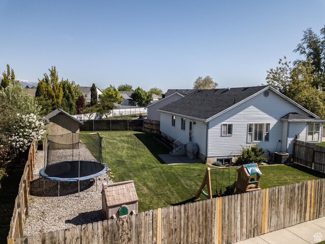 rear view of property featuring a trampoline, roof with shingles, and cooling unit